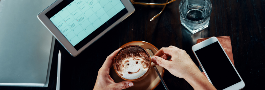 Woman looking at calendar on tablet while drinking coffee