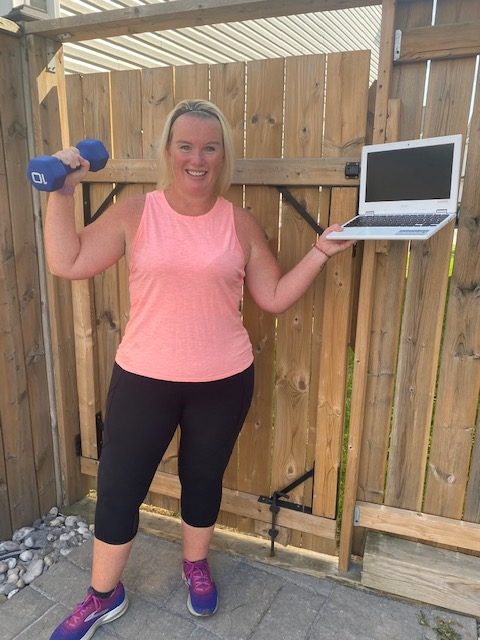 Cari Gangaram holding a 10 lb weight and a laptop