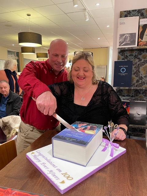 Author Kate Hardy cutting a cake with the image of Tempted by Her Fake Fiance on the icing