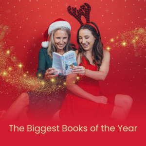A photo of two women reading a harlequin book. The one on the left is wearing a santa hat while the one on the right is wearing fake antlers. Overtop is text reading The Biggert Books of the Year