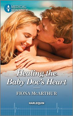 Cover image for Healing the Baby Doc's Heart by Fiona McArthur, featuring a man and a woman lying next to each other on the beach. The man is kissing the woman's forehead. She is smiling. 
