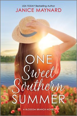 Cover image for One Sweet Southern Summer by Janice Maynard, featuring a woman with long brown hair and her back towards the camera. She is looking up at the sunny sky and holding a straw sunhat on her head. She is surrounded by flowers and a lake in the background. 