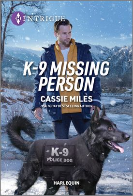 Cover image for K9 Missing Person by Cassie Miles, featuring a man and a K-9 in a police dog vest standing in the snow at night. There are mountains in the background.