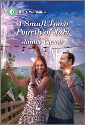 Cover image for A SMALL TOWN FOURTH OF JULY by Janice Carter, featuring a man and woman playing with sparklers on a patio. There are fireworks going off in the night sky behind them.